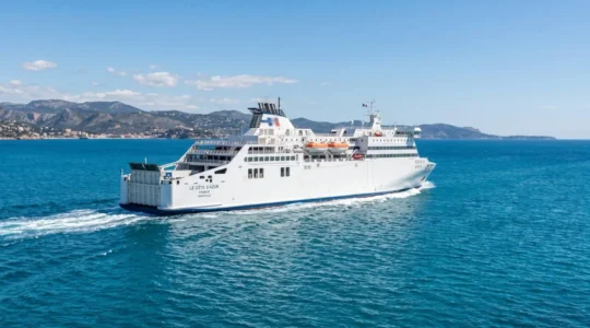 Un ferry moderne naviguant en pleine mer Méditerranée sous un ciel dégagé, eaux bleues turquoise, architecture navale contemporaine